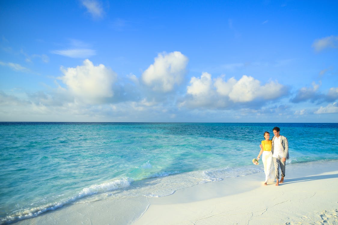 Couple walking on a beach (Photo via Pexels.com)